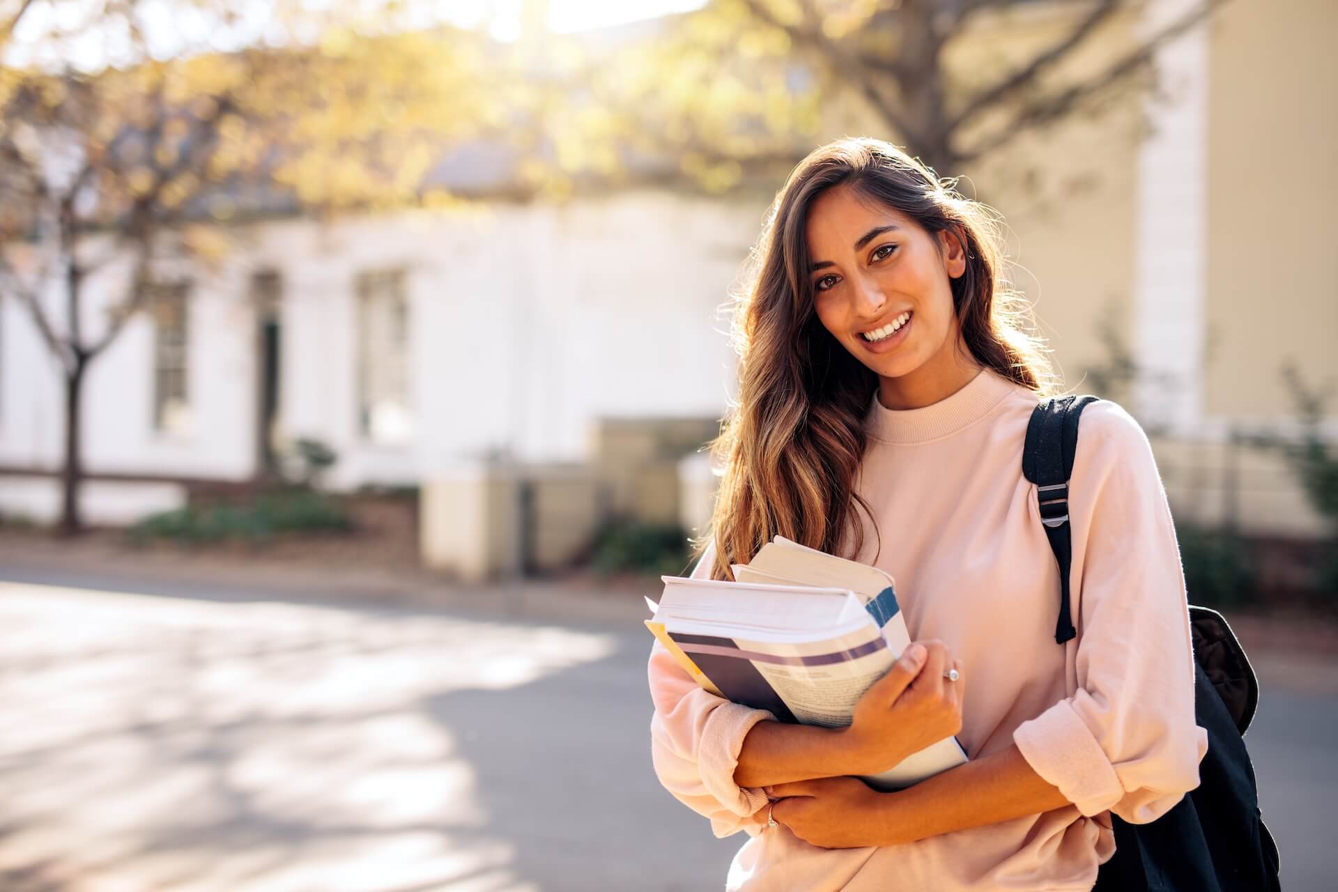 Young woman holding books outdoors representing proactive fertility awareness and family planning advice for women in their 20s