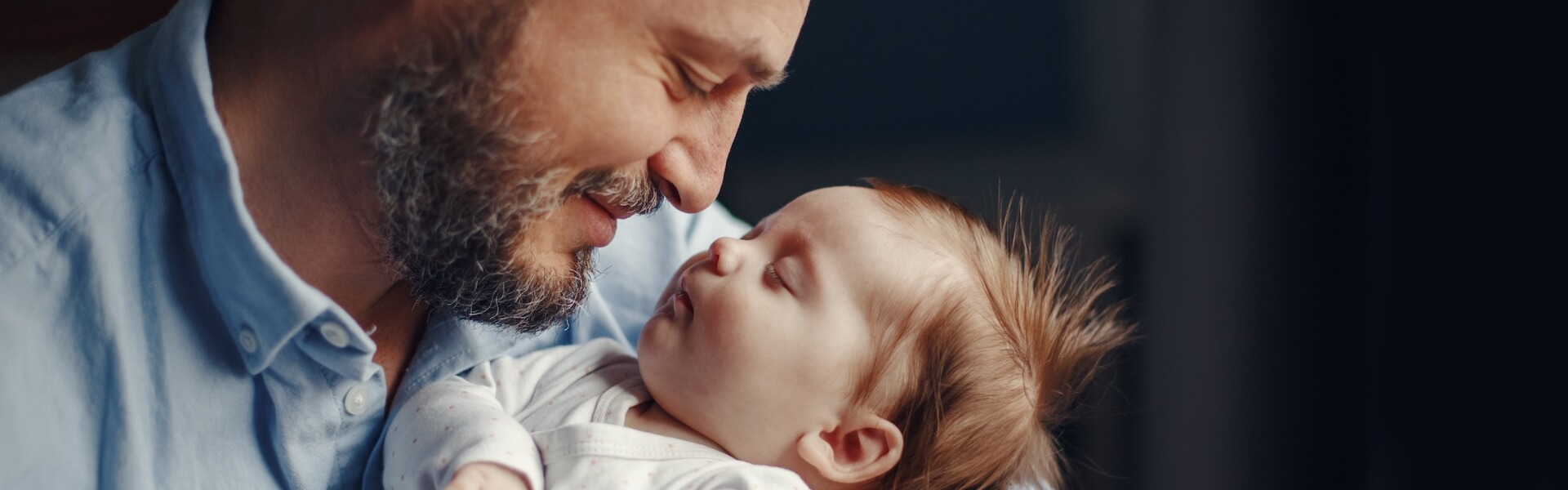 Father tenderly holding newborn baby representing the hope and success of male fertility treatment and fatherhood