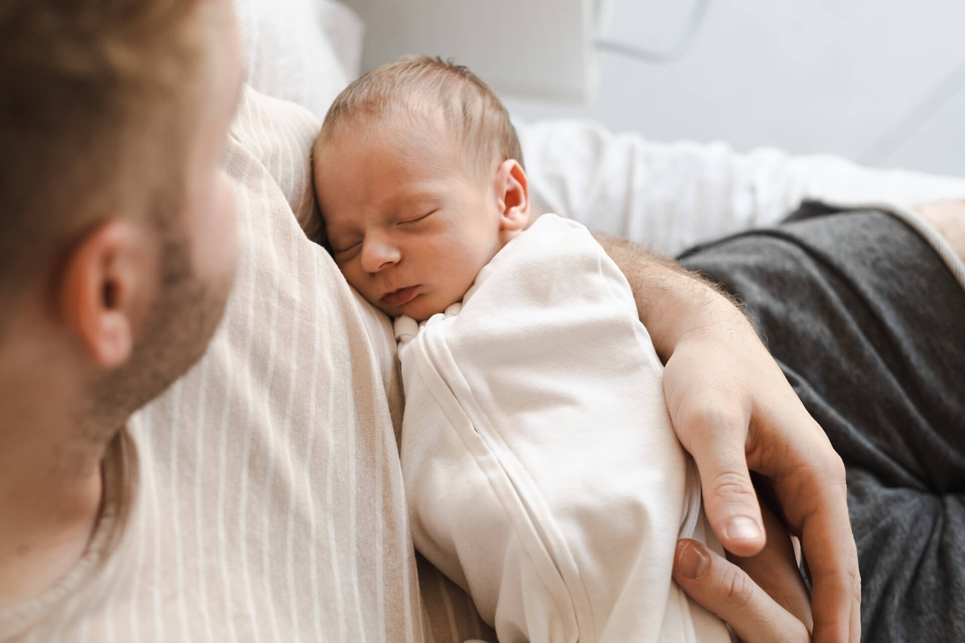 Father tenderly holding sleeping newborn baby representing the hope and success of male fertility treatment at The Fertility Center of Las Vegas