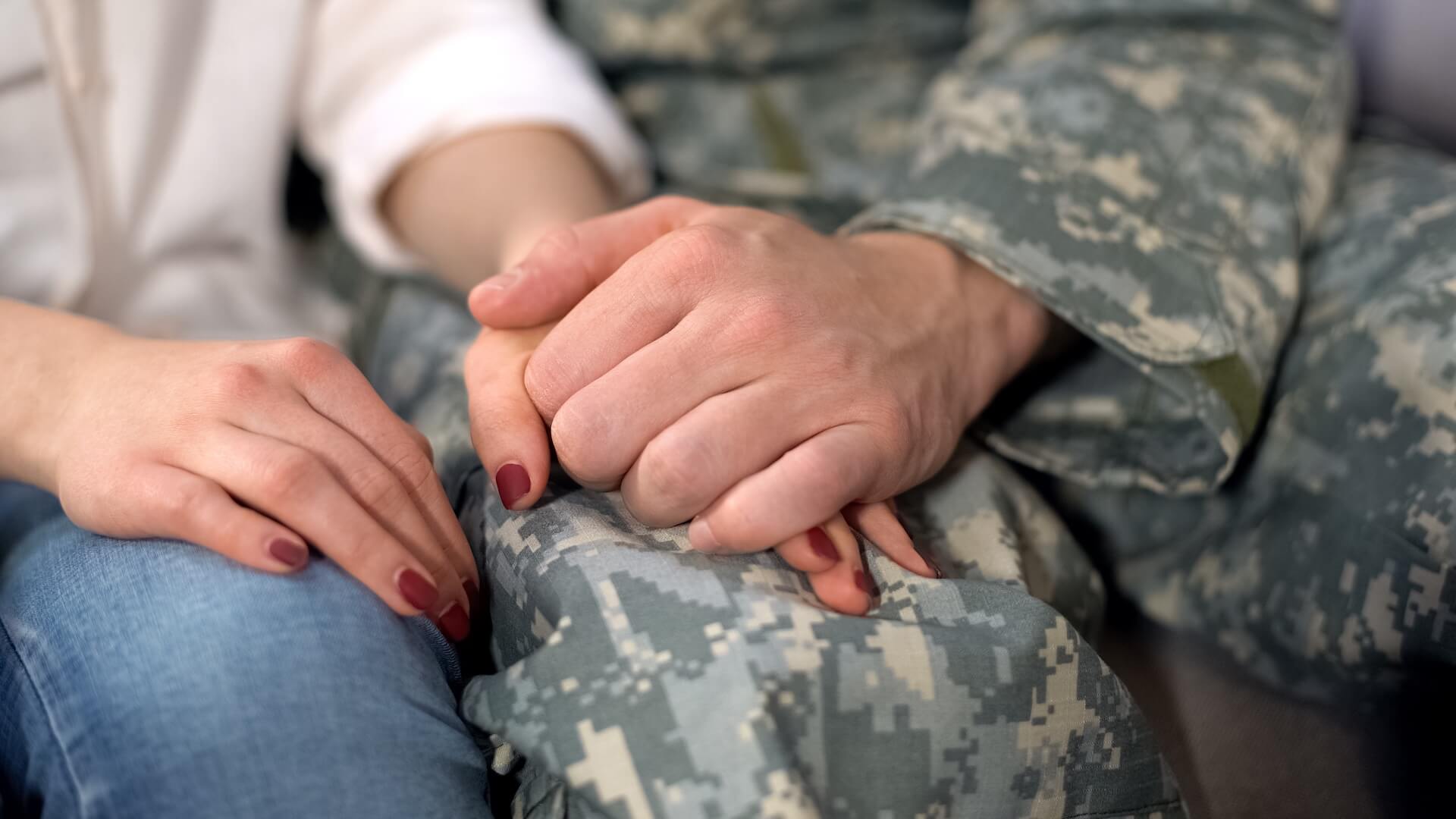 Couple holding hands with partner in military uniform representing fertility treatment assistance and support for veterans