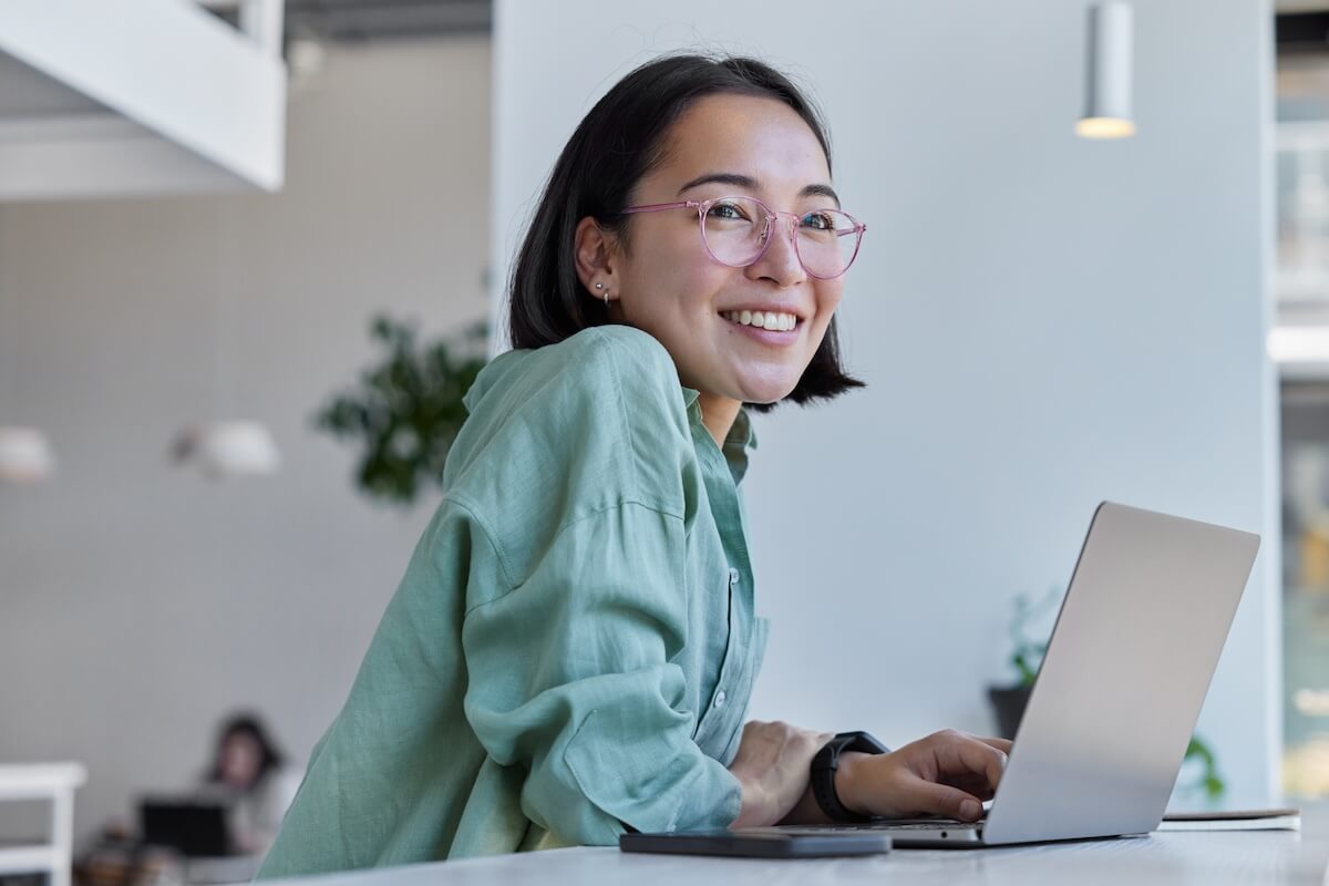Smiling woman using a laptop, representing access to fertility benefits and insurance coverage