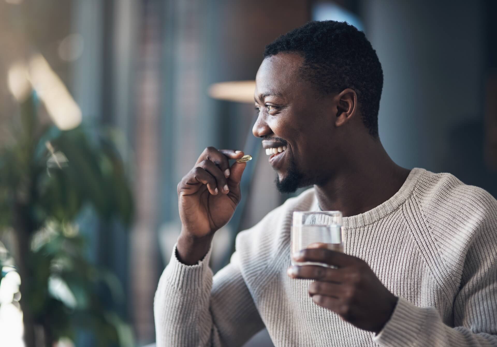 Man taking supplement capsule with glass of water representing fertility supplements for men and their role in conception support