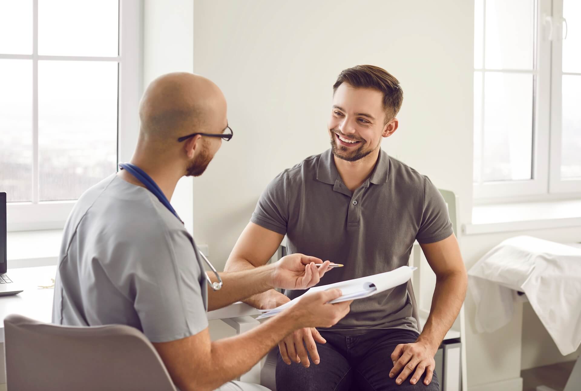 Man smiling during consultation with doctor reviewing male fertility results and treatment options