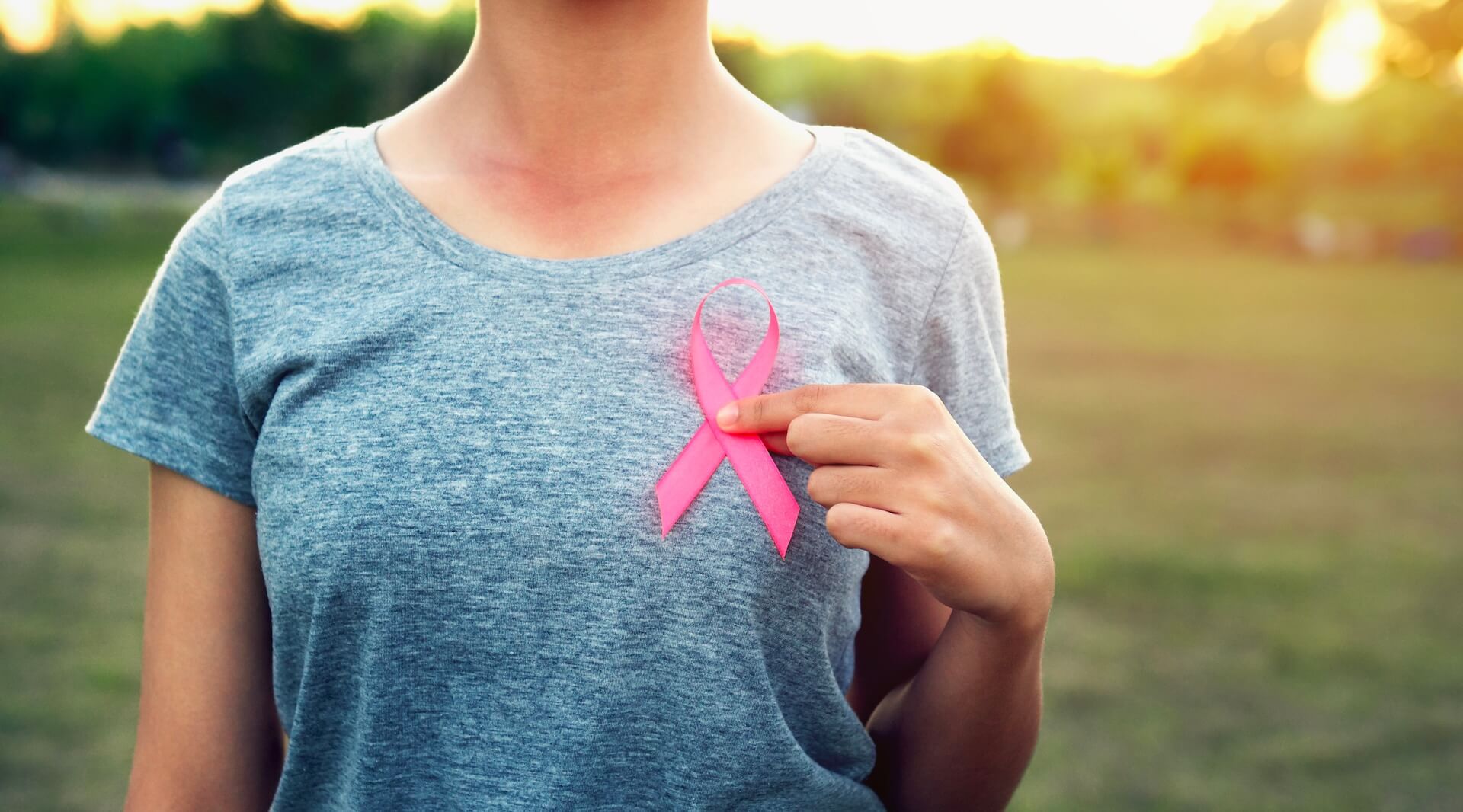 Woman wearing pink breast cancer awareness ribbon representing hope for fertility preservation and oncofertility options