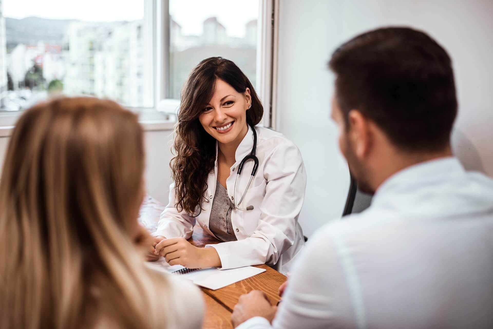 Fertility doctor in warm personal consultation with patient at physician-owned fertility clinic