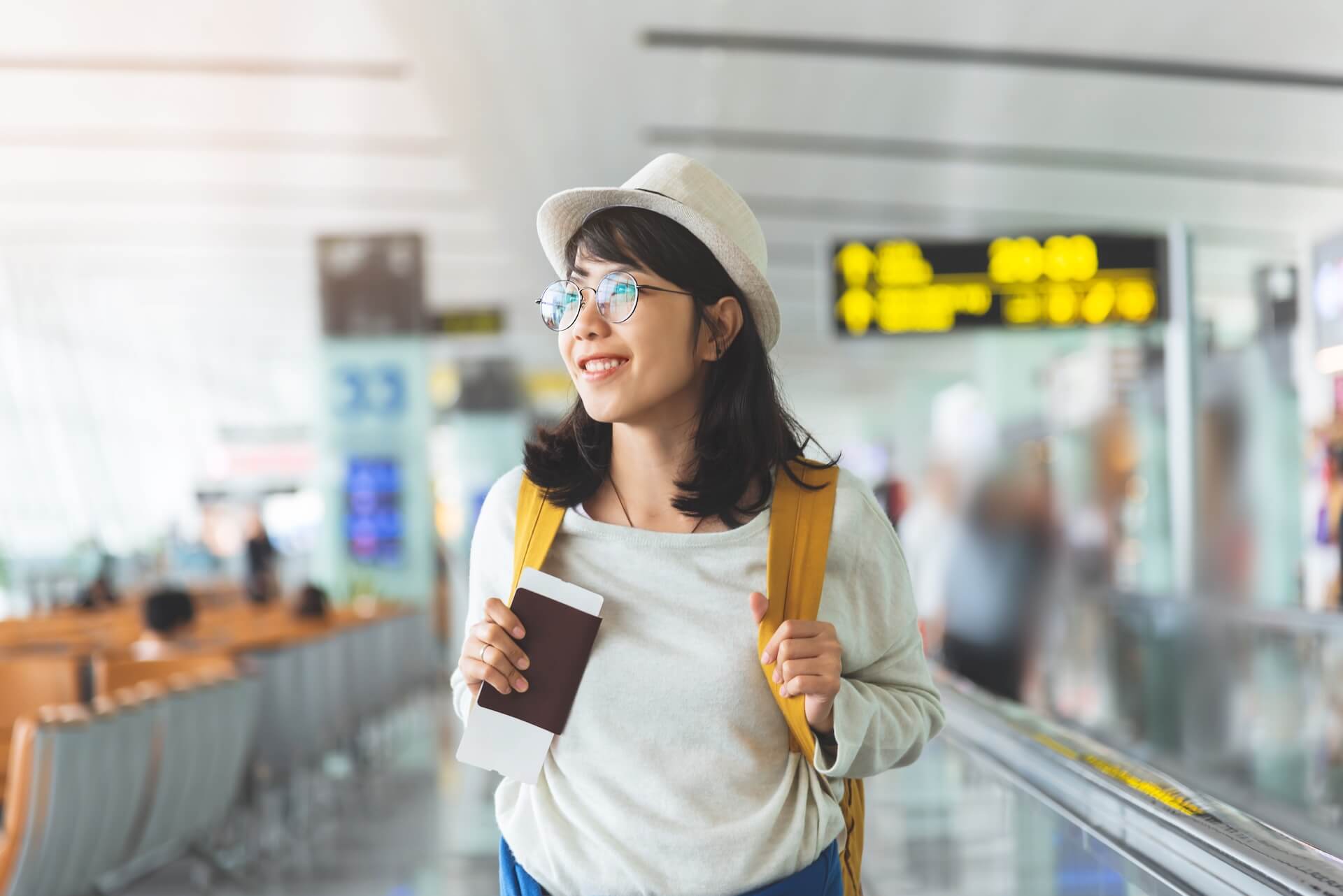 Woman smiling at airport holding passport and boarding pass preparing to travel during IVF fertility treatment