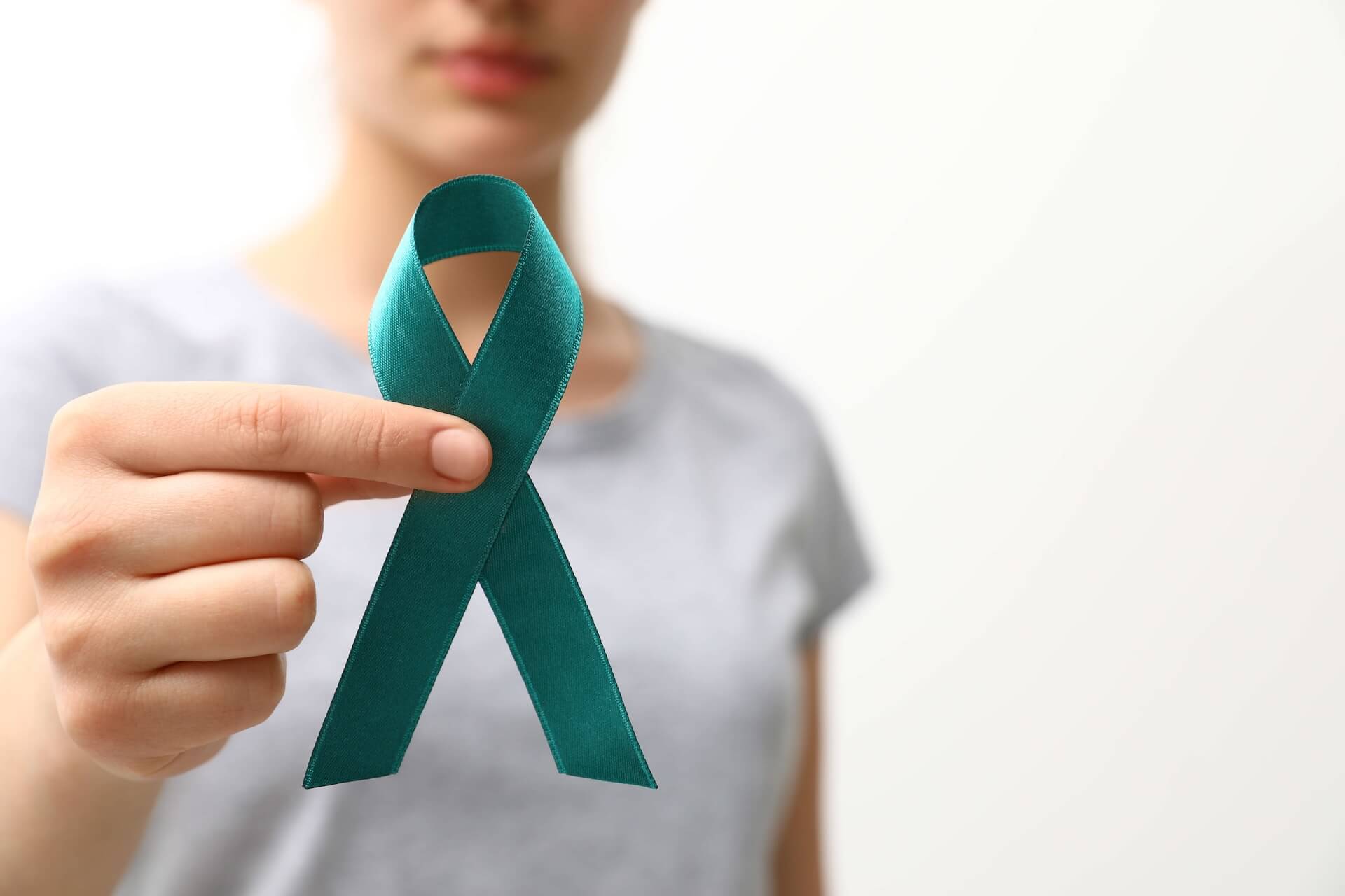 Woman holding teal cervical cancer awareness ribbon representing hope for fertility after cancer treatment